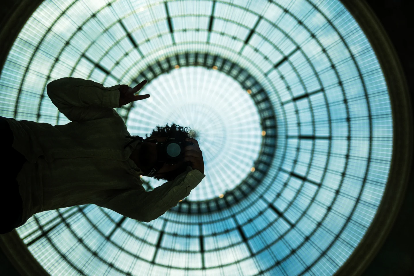 Daniel holding his camera beneath a circular glass ceiling in Paris