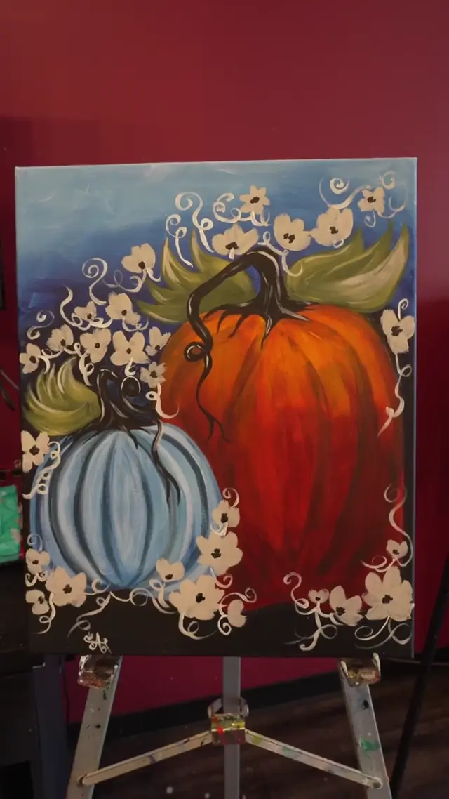 Finished floral pumpkin painting on an easel in the studio