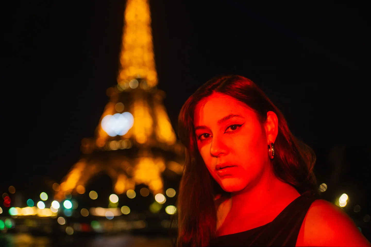 Red-lit portrait of Andrea against Eiffel Tower lights
