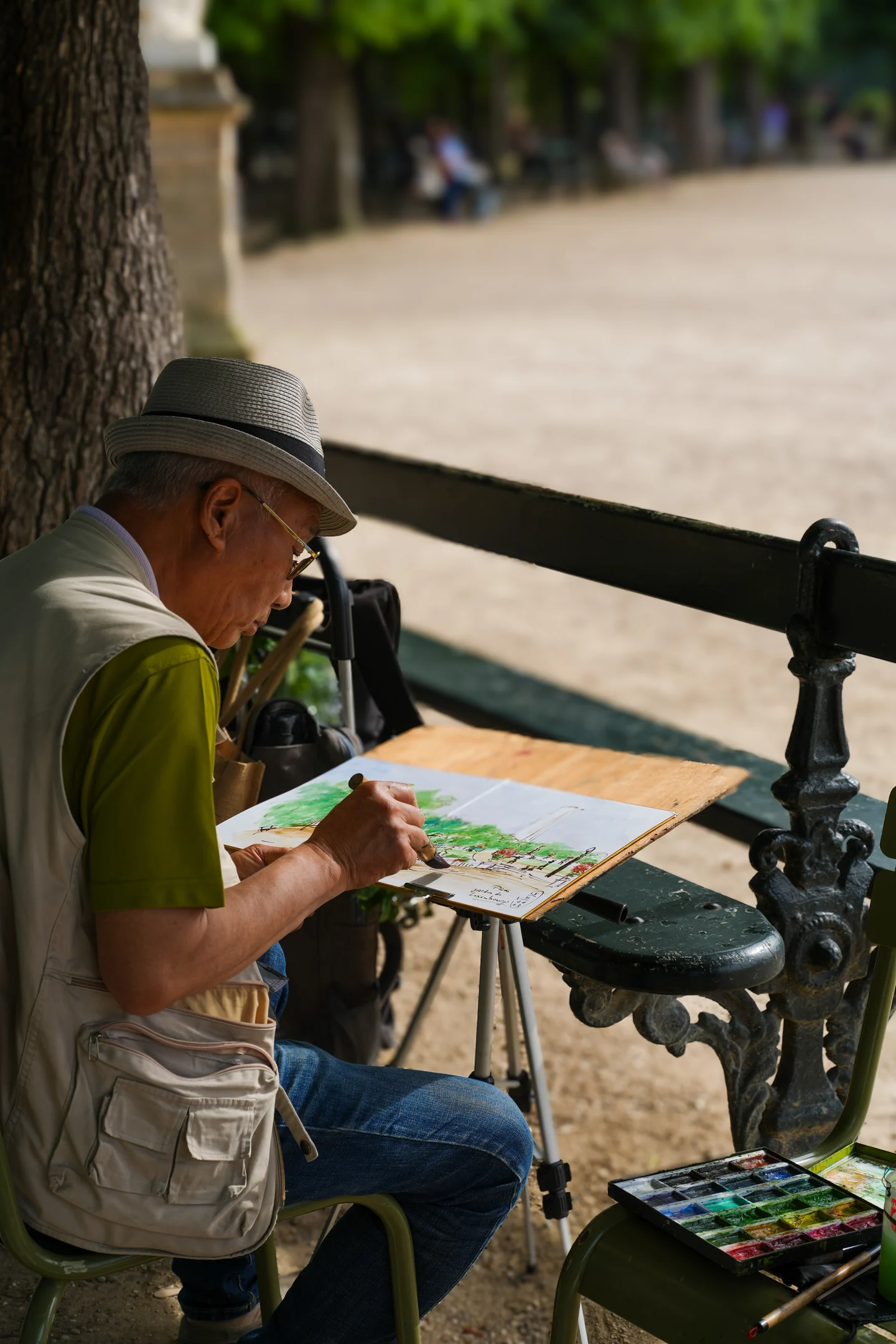 A street artist painting beside a park bench in Paris